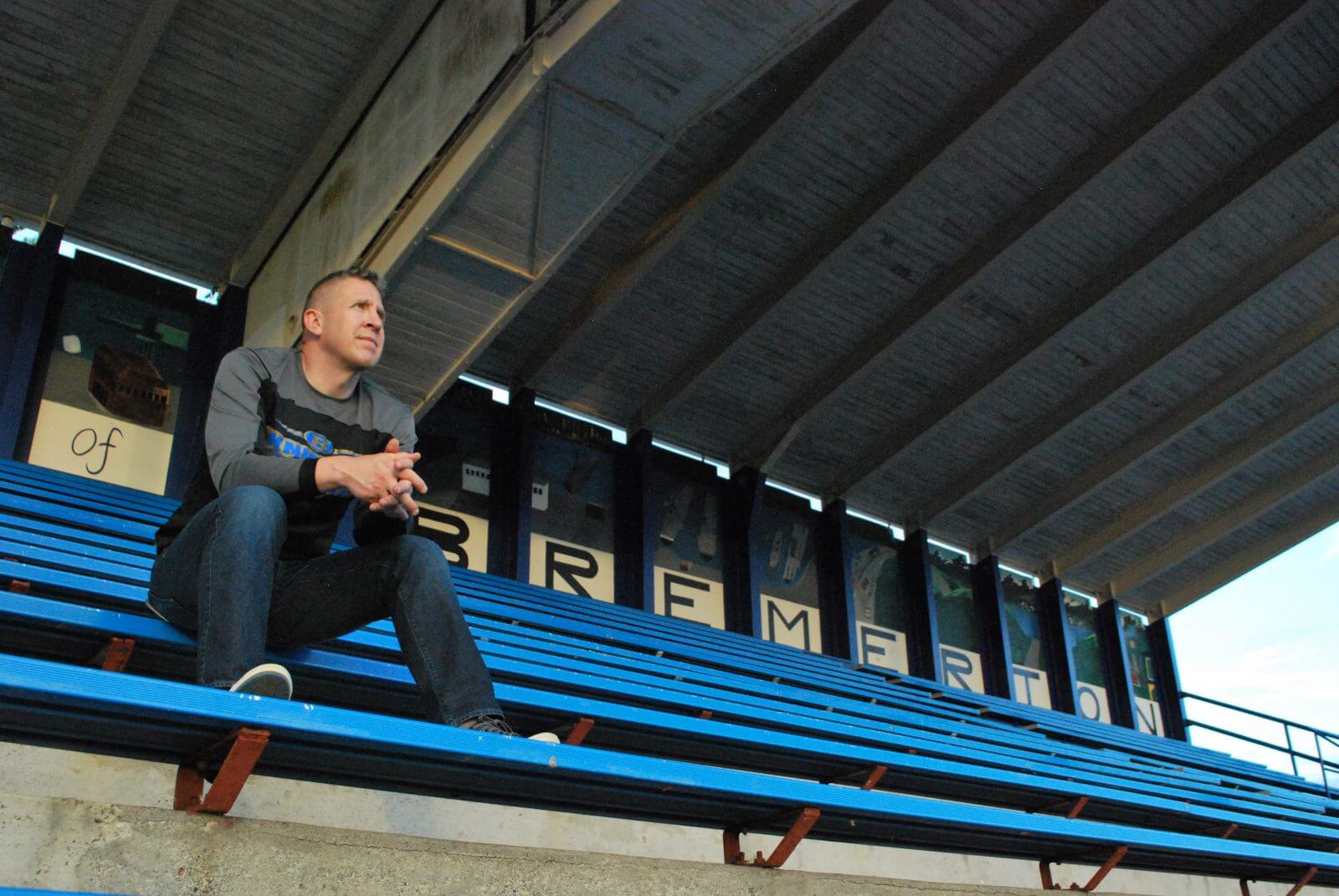 Former assistant varsity football coach Joe Kennedy sits in the stands of the Bremerton High School football field.