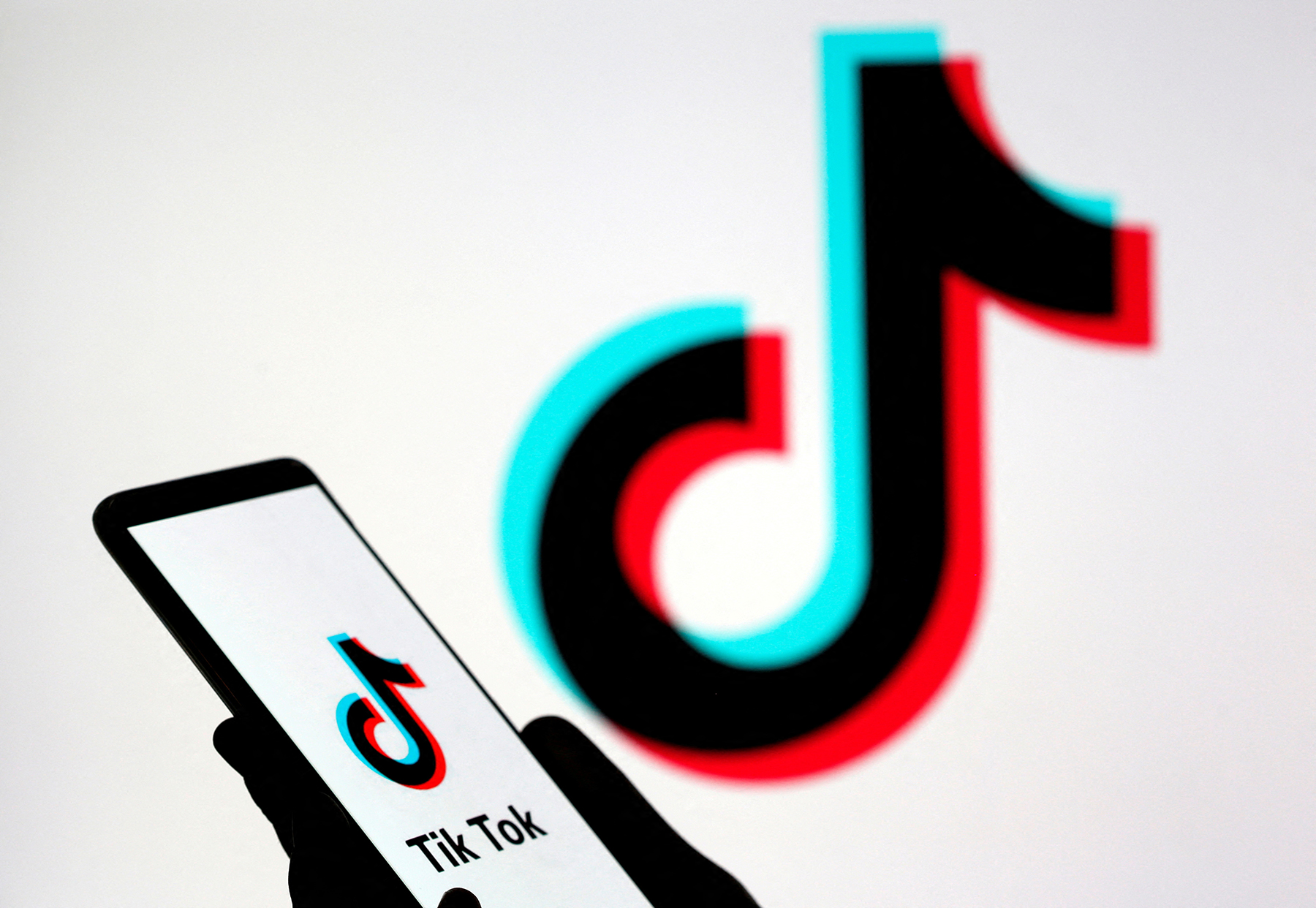 Person holds a smartphone with Tik Tok logo displayed in this picture illustration