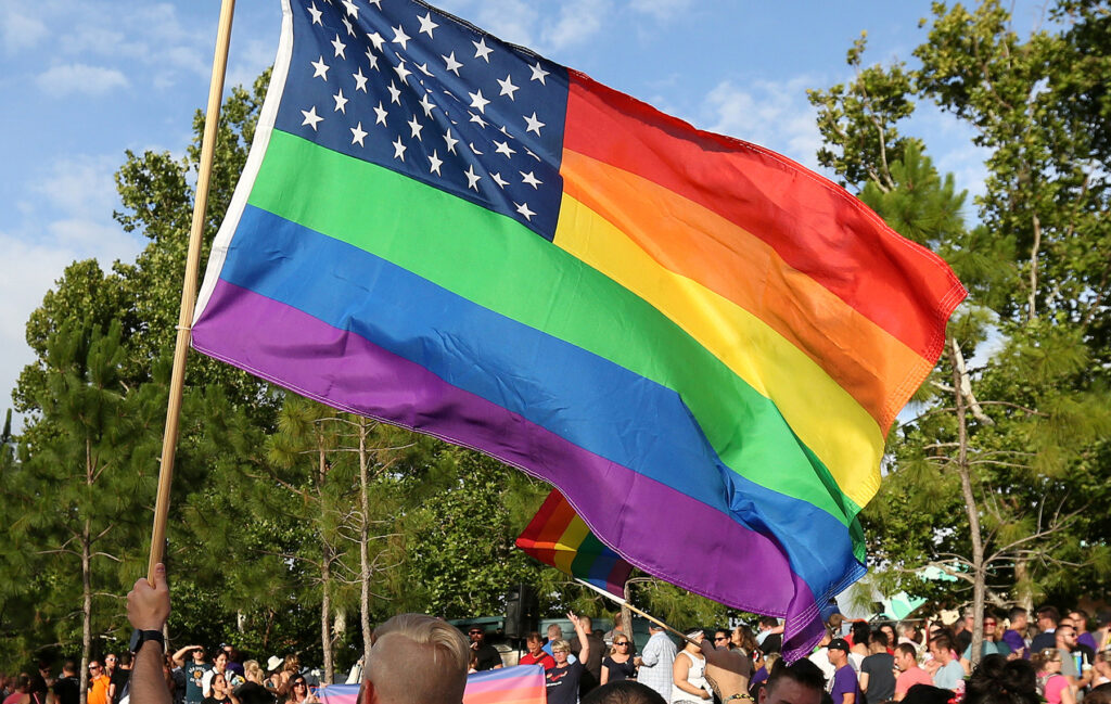 A rainbow U.S. flag is held up during a vigil for the Pulse night club victims in Orlando