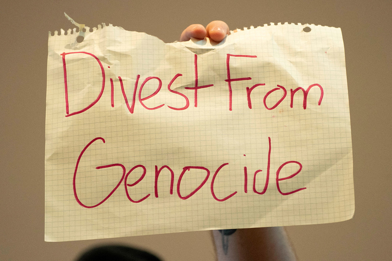 a demonstrator holds a sign in support of the Palestinians during a Board of Regents meeting at the University of Washington