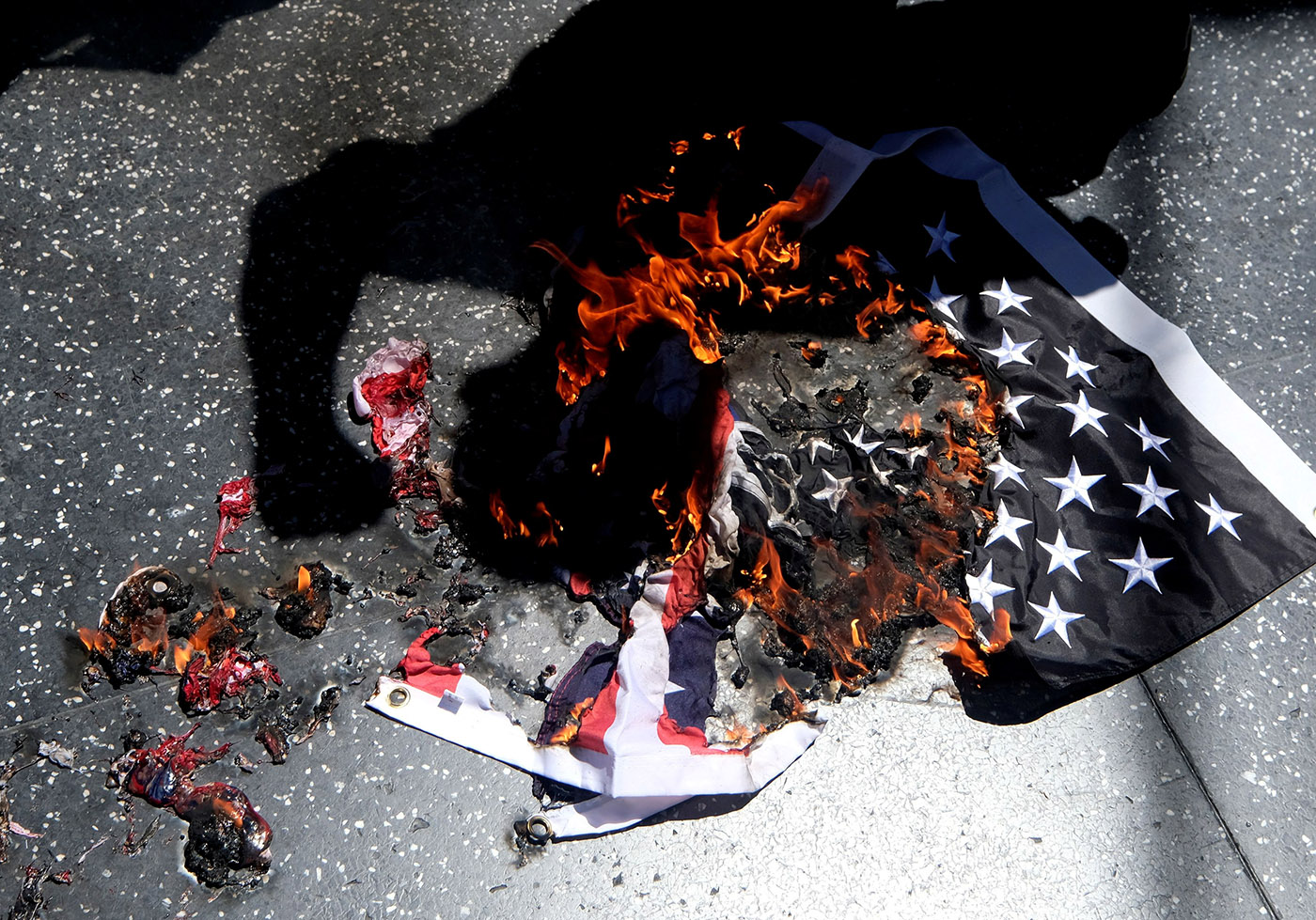 The shadow of Gregory "Joey" Johnson casts on a burning U.S. flag near Donald Trump's star on the Hollywood Walk of Fame