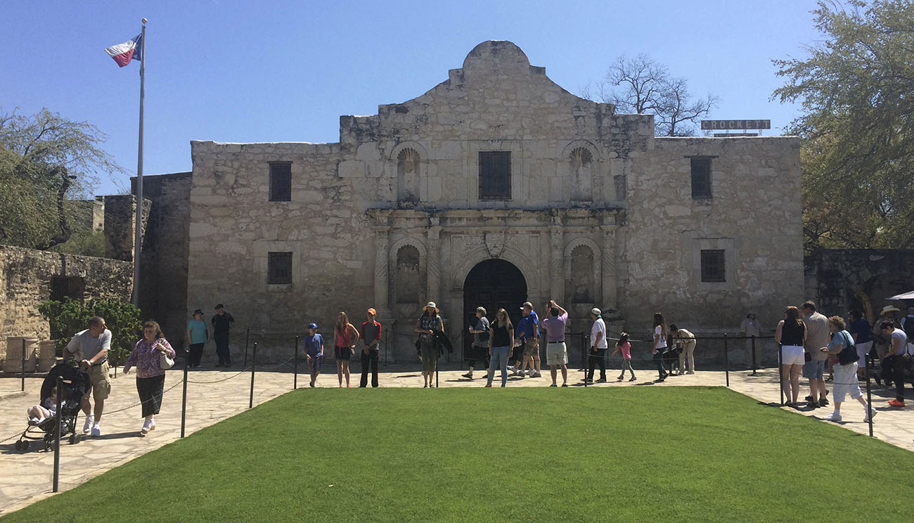Visitors walk at the entrance to the Alamo, the most-visited tourist site in the state, in San Antonio