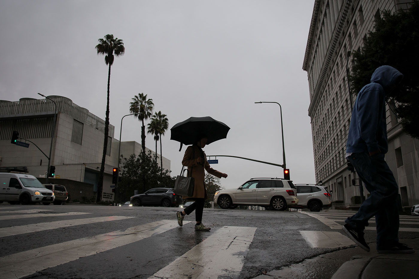 Pedestrians cross a street as it rains in Downtown Los Angeles